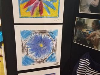 A student exhibit panel showing three photos of a young female student designing and making a navy and navy blue and white short sleeved, knee length dress. The panel also shows three student flower drawings