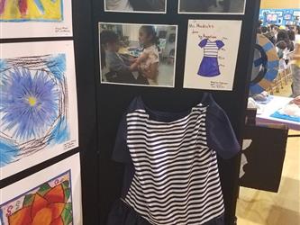 A student exhibit panel showing three photos of a young female student designing and making a navy and navy blue and white short sleeved, knee length dress. The panel also shows three student flower drawings